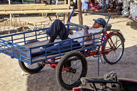 A man resting on a cart in a sunny market environment, The market in the streets of Nasca in Peru
