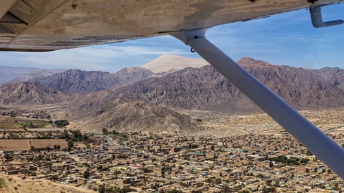 Aerial view of a city surrounded by mountains, viewed from the window of an airplane in clear