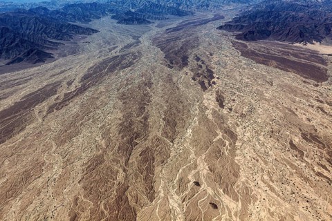 Impressive aerial view of a desert landscape with many earthy textures and furrows, central focus