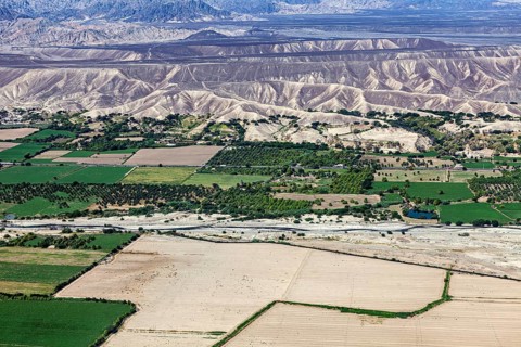 Extensive green areas and riverbed with mountain ranges on the horizon, the desert landscape near