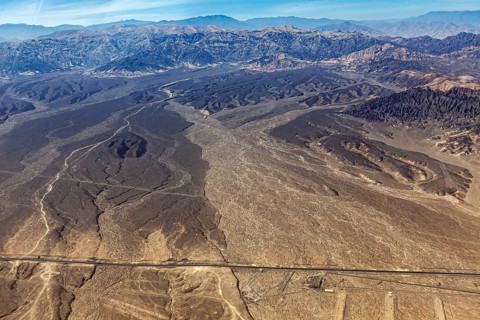 Extensive desert landscape with a long straight road, captured from above, The desert landscape