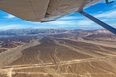 View from an airplane of a dry desert landscape with mountains and blue sky, The desert landscape
