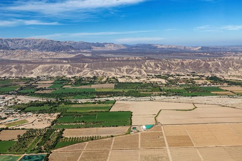 View of a mix of fields and dry landscapes with mountain range, The desert landscape near Nasca in