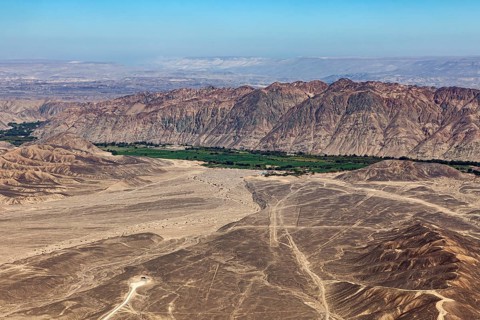 Dramatic desert plain with tracks and mountain panorama under clear sky, the desert landscape near
