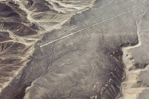 Geoglyphs in a vast sandy desert landscape with mountains, seen from the air, The geoglyphs and