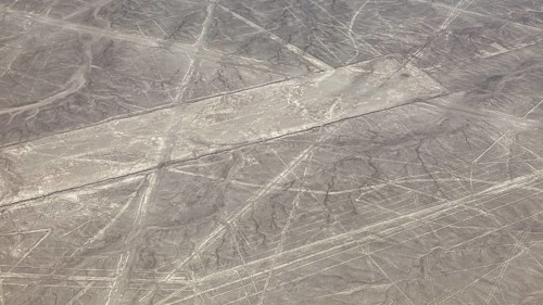 Aerial view of the Nazca lines in a barren desert landscape with geometric patterns, the geoglyphs