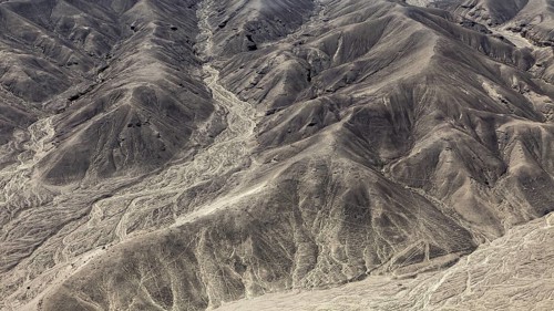 Hilly desert landscape with numerous engraved lines, geoglyphs and drawings in the desert near