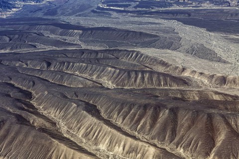 Aerial view of dry, folded mountains in a desert-like landscape, the desert landscape near Nasca in