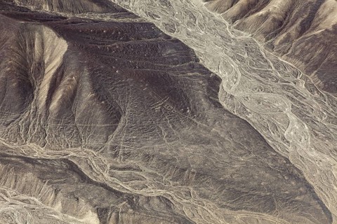 Detailed geoglyphs on a desert plain with adjacent mountain range, the geoglyphs and images in the