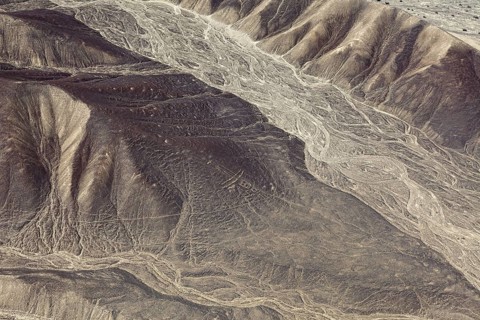 Aerial view of a desert with hills and ancient line formations, the geoglyphs and images in the
