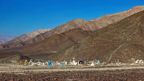 Cemetery in a desert-like landscape in front of a mountain range under clear skies, cemetery in the