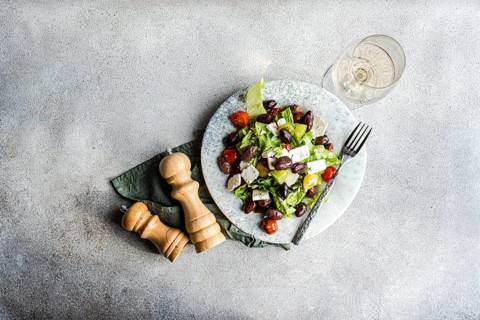 A vibrant Greek salad with tomatoes, lettuce, fermented olives, feta cheese, and olive oil