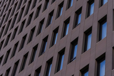 A detailed view of a modern building facade featuring a repetitive geometric pattern with aligned
