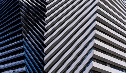 A close view of a modern skyscraper demonstrates contrasting architectural details, featuring