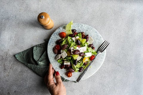 A vibrant Greek salad featuring tomatoes, lettuce, fermented olives, and feta cheese