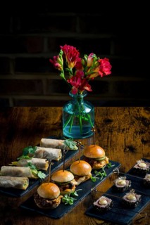 Elegant display of vegetable and courgette rolls, pulled pork and cabbage mini burgers, and rare