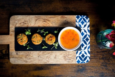 Top-down view of golden corn and spring onion patties served with a bowl of sweet chili sauce,