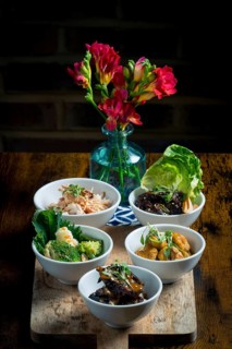 A selection of vibrant Asian cuisine bowls arranged on a wooden board The dishes feature