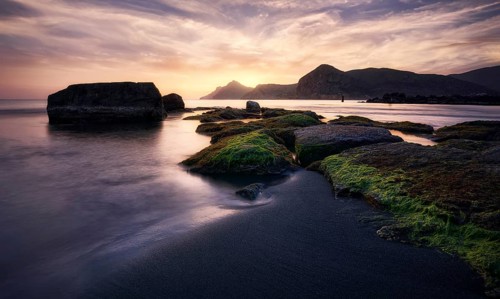 Sunrise casts golden hues over the rocky shoreline of Cala del Lastre in Portman, Murcia The