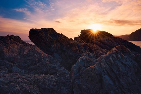 At Cala del Lastre, Portman in Murcia, Spain, a breathtaking sunset casts warm hues over rugged