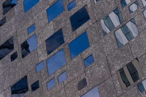 Detailed view of a modern building facade showcasing varying window sizes and a textured exterior