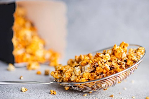 Gourmet sweet caramel popcorn in a shiny wire basket, the sugary golden pieces bathed in caramel