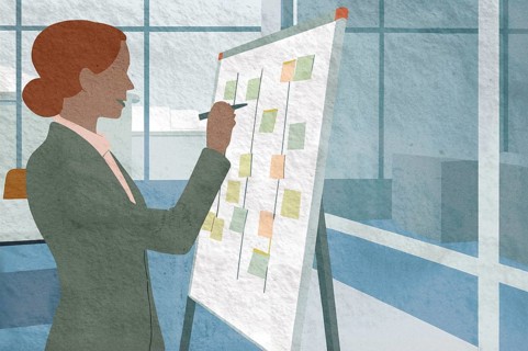 A business professional is writing on a flip chart in a bright office space She is illustrating
