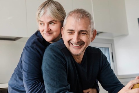 A joyful senior couple shares a tender moment, embracing in their modern kitchen The scene captures
