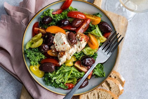 Top view of a nutritious salad featuring raw Kale leaves, multi-colored cherry tomatoes, sliced red