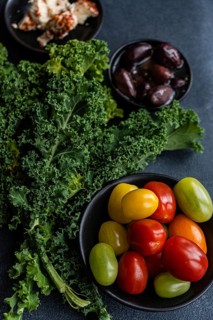 Top view of a healthy salad featuring raw kale leaves, a mix of colorful cherry tomatoes, red onion