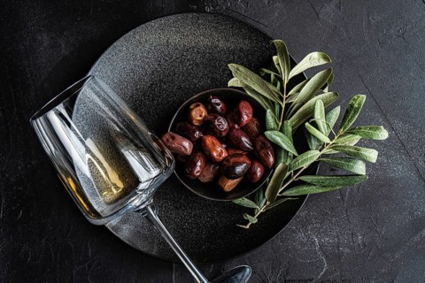 Top view of a sophisticated arrangement featuring Greek BBQ olives nestled in a black bowl with