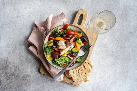 Top view of a salad featuring raw kale, assorted cherry tomatoes, red onion slices,