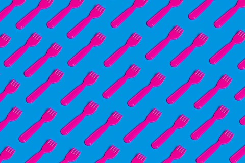 A vivid pattern of pink plastic forks on a blue background highlights the critique of junk food