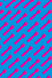Rows of pink plastic cutlery on a blue background symbolizing the artificiality and environmental