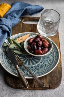 A tasteful arrangement of Greek BBQ olives on a ceramic plate, accompanied by a glass, rustic