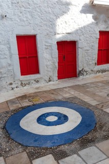 Bright red doors and white wall of typical traditional architecture with a blue and white symbol to