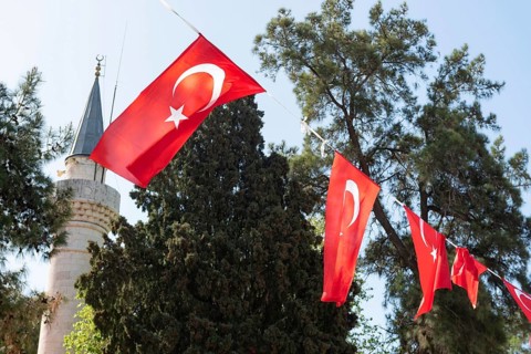 Bodrum, Turkey. April 23rd 2022 Turkish national flag fluttering in front of an Islamic minaret of