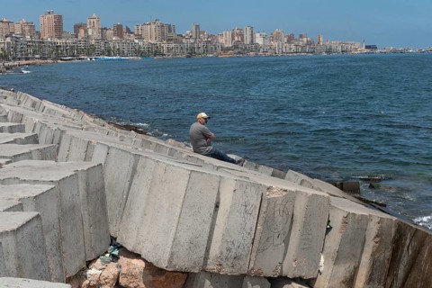 A man sits alone on the concrete breakwater, a barrier for potential flooding, the Egyptian