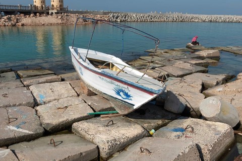 Alexandria, Egypt. December 1st 2022 Wooden boat abandoned on large concrete slabs designed to