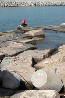 Alexandria, Egypt. December 1st 2022 Muslim women wearing a pink hijab sitting on large concrete