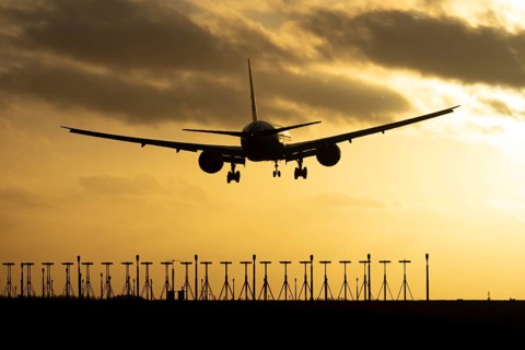 Boeing 777 commercial passenger jet aircraft in flight on approach to land over runway lights