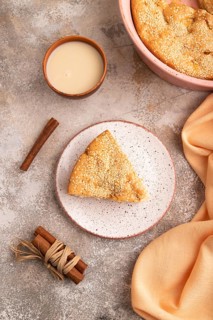 Apple Charlotte cake on brown concrete background and orange linen textile, cup of milk, top view,