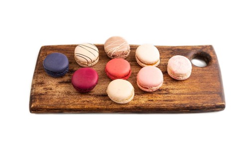Macarons colourful cookies dessert on brown wooden cutting board Isolated on white, close up, side