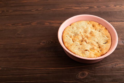 Apple Charlotte cake in baking dish on brown wooden background, top view, flat lay, close up