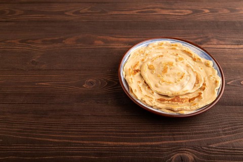 Stack of Plain Fried pancakes on brown wooden background. side view, copy space