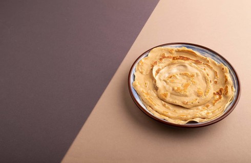 Stack of Plain Fried pancakes on gray and beige pastel paper background. side view, copy space