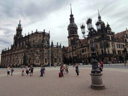 People gather in front of the historic ensemble of buildings in Dresden under a cloudy sky, Dresden