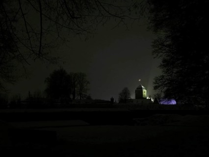 Dark, silent night scene with the dimly lit Rosenberg Fortress behind the trees, Kronach,