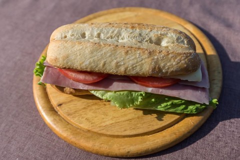 Ham and cheese baguette on a wooden plate, Italy