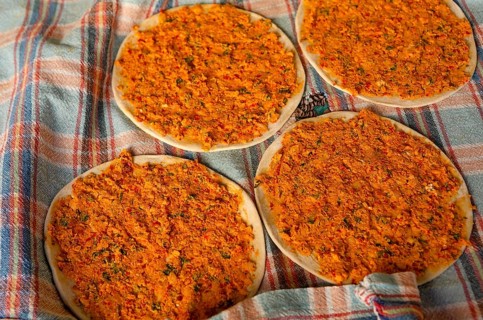 Traditional Turkish Biberli Ekmek Flat bread with red pepper paste being prepared before cooking in